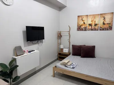 a living room with a bed and a tv at Prime Location Affordable Studio Condo in Legaspi village, Makati with Fast WiFi in Manila