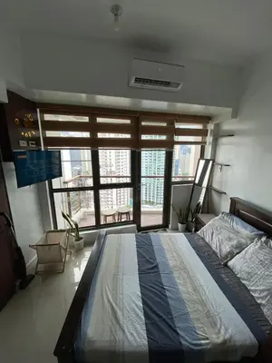 a bedroom with a large bed and a large window at Prime Location and Affordable Studio Condo in Legaspi Village, Makati with City view in Manila
