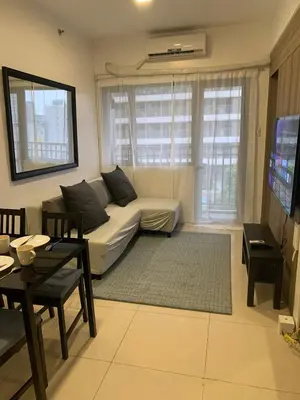 a living room with a white couch and a tv at Fame Tower1 2-Bedrooms All Rms w Aircon Washer Balcony in Manila