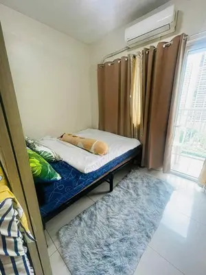 a small bedroom with a bed and a window at Breeze Residences in Manila