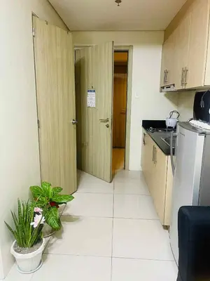 a small kitchen with a door open to a room at Breeze Residences in Manila