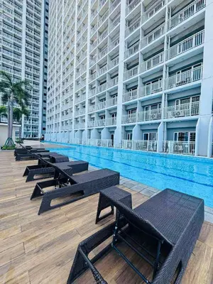a row of benches next to a swimming pool in a building at Breeze Residences in Manila