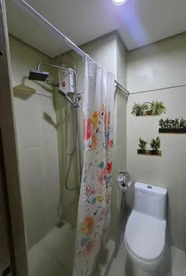 a bathroom with a shower curtain and a toilet at Sojourn in S Residences in Manila