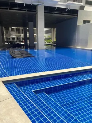 a swimming pool with blue tiles in a building at Sojourn in S Residences in Manila