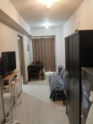 a living room with a tv and a chair at Sojourn in S Residences in Manila