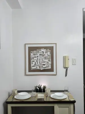 a table with plates and glasses and a picture on the wall at Gracie's Suites by Staycation With FREE Parking in Manila