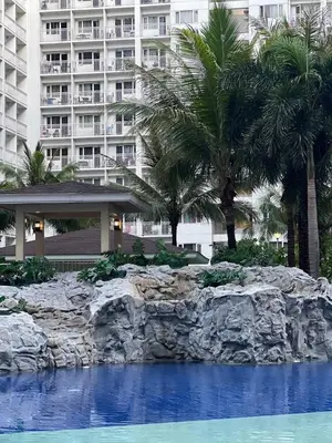 a resort with palm trees and a swimming pool at Gracie's Suites by Staycation With FREE Parking in Manila