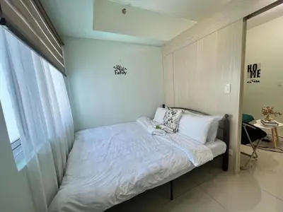 a small bedroom with a bed with white sheets and pillows at cozy green in Manila