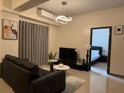 a living room with a black couch and a television at Luxurious Modern Cozy Manila Bayview Pool View 1 2 3 Bedrooms Near Manila Airports Okada Solaire MOA in Manila