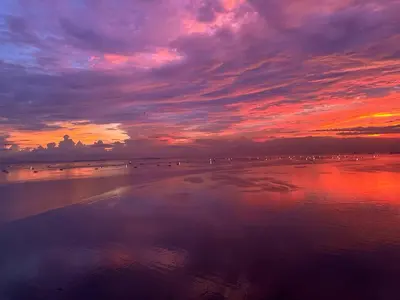 a sunset on a beach with people in the water at Luxurious Modern Cozy Manila Bayview Pool View 1 2 3 Bedrooms Near Manila Airports Okada Solaire MOA in Manila