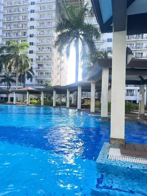 a large blue swimming pool with palm trees and buildings at Moa shell residence pasay city in Manila
