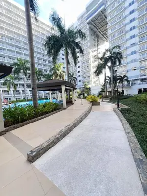 a walkway in a city with palm trees and buildings at Moa shell residence pasay city in Manila