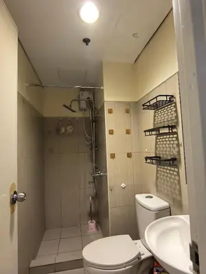 a bathroom with a shower and a toilet and a sink at Shell Residence Moa in Manila