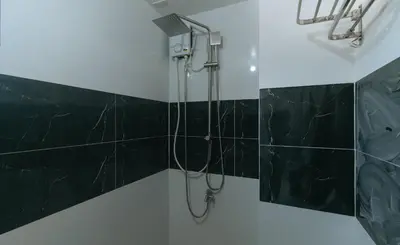 a bathroom with a shower with black tiles at Sans Hotel near Enchanted Kingdom Santa Rosa Laguna in Santa Rosa