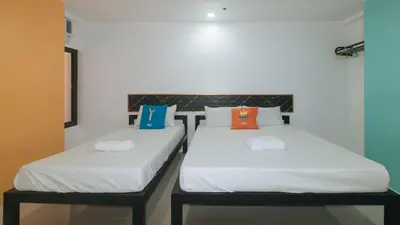 two beds in a room with white sheets and colorful pillows at Sans Hotel near Enchanted Kingdom Santa Rosa Laguna in Santa Rosa