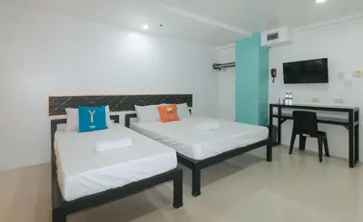 a room with two beds and a desk in it at Sans Hotel near Enchanted Kingdom Santa Rosa Laguna in Santa Rosa
