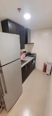 a kitchen with a white refrigerator and black cabinets at JACC Condotel in Manila