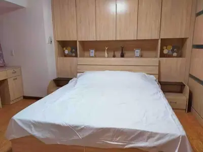 a bedroom with a large white bed with wooden cabinets at R&R Empire Rental Unit in Manila
