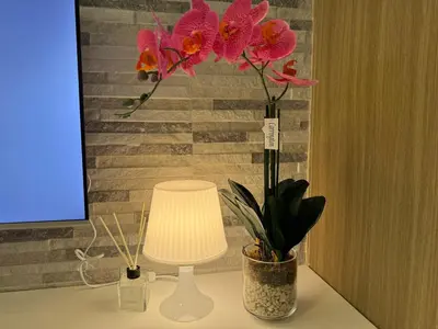 a table with a lamp and a vase with flowers at Home of Mari in Shore 2 Residences Room 10107 near Airport, SM MOA, US Embassy Manila by Prime Stay MOA in Manila