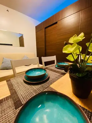 a dining room table with plates and a plant on it at Skyline Blue Air residences 1Br cityview by Tin & Aix in Manila