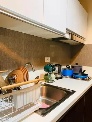 a kitchen counter with a sink and a dish rack at Skyline Blue Air residences 1Br cityview by Tin & Aix in Manila