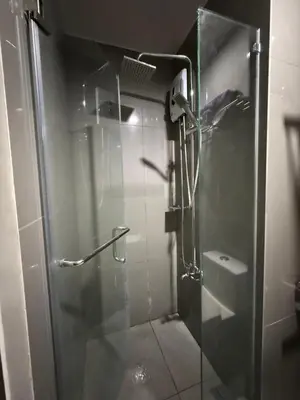 a shower with a glass door in a bathroom at Skyline Blue Air residences 1Br cityview by Tin & Aix in Manila