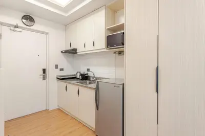 a white kitchen with a sink and a refrigerator at Central Modern Cosy Condo in Makati - The Linear Suite in Manila
