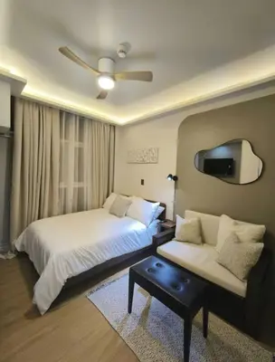 a bedroom with two beds and a couch and a ceiling fan at Central Modern Cosy Condo in Makati - The Linear Suite in Manila