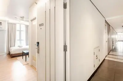 a hallway with white walls and a room with a bed at Central Modern Cosy Condo in Makati - The Linear Suite in Manila