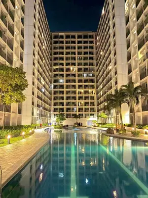 a swimming pool in front of a large building at Shore Condotel pasay manila in Manila