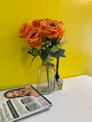 a vase with orange roses on a table next to a magazine at Lemon Room in S Residences near MOA, Airport, US Embassy by Prime Stay in Manila
