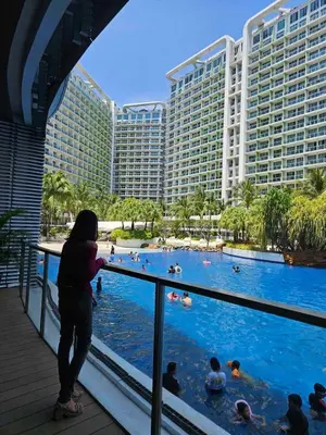 a woman standing in front of a swimming pool at a hotel at A2Z Staycation Miami Tower 15th Floor With Ps4 and Netflix in Manila