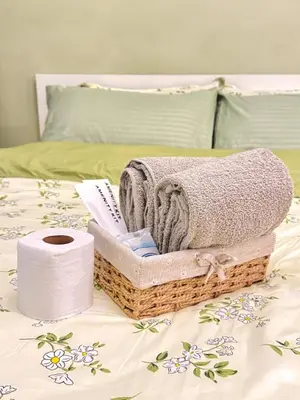 a basket of towels and a roll of toilet paper on a bed at 1BR with Pool View Near NAIA Long Stay Ready in Manila