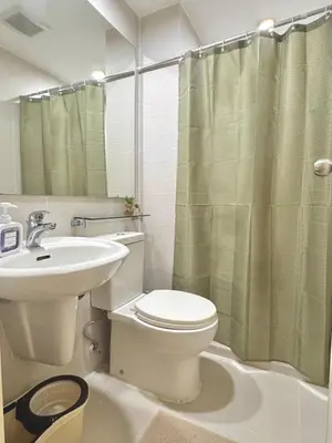 a bathroom with a toilet and a sink and a shower at 1BR with Pool View Near NAIA Long Stay Ready in Manila