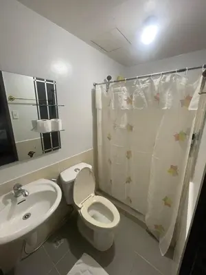 a bathroom with a white toilet and a sink at A Venue Residences 1509 in Makati