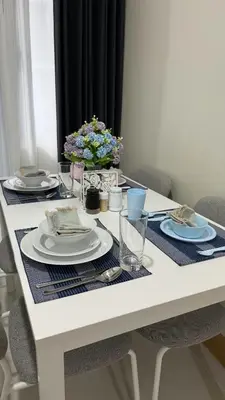 a white table with plates and a vase of flowers at Modern 1-BR Retreat with Pool, High Speed Wifi, Netflix, steps from MOA, Bars, Entertainment, Transport in Manila