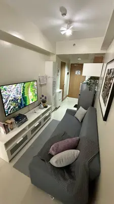 a living room with a couch and a flat screen tv at Modern 1-BR Retreat with Pool, High Speed Wifi, Netflix, steps from MOA, Bars, Entertainment, Transport in Manila