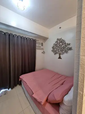 a bedroom with a bed and a tree on the wall at My little Apartment in Manila
