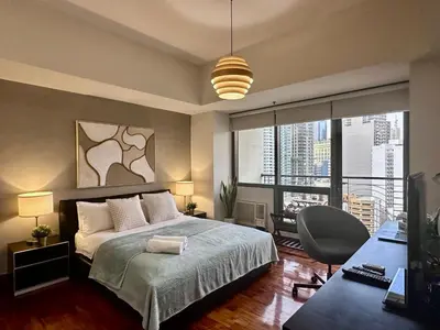 a bedroom with a bed and a large window at 1BR Corner Unit with Balcony in Manila