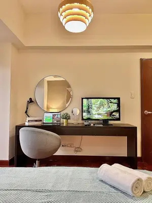 a bedroom with a desk with a mirror and a chair at 1BR Corner Unit with Balcony in Manila