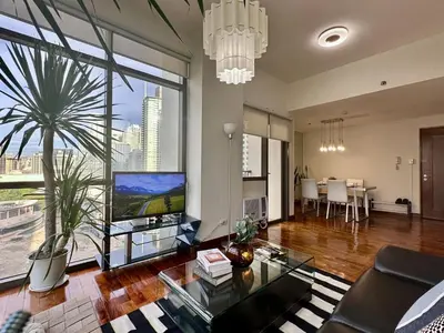 a living room with a large window and a large tv at 1BR Corner Unit with Balcony in Manila