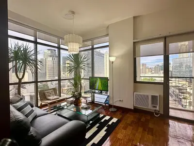 a living room with a couch and large windows at 1BR Corner Unit with Balcony in Manila