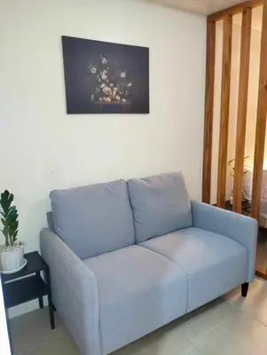 a blue couch in a living room with a painting on the wall at Studio Near Mall & Airport! in Manila