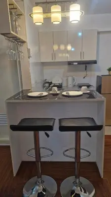 a kitchen with a counter with two bar stools at 1BR with Netflix, Prime & KTV in Manila