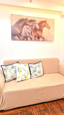 a couch with three paintings of horses on the wall at 1BR with Netflix, Prime & KTV in Manila