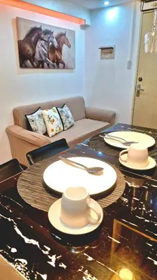 a living room with a table with plates on it at 1BR with Netflix, Prime & KTV in Manila