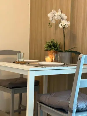 a white table with a vase of flowers on it at City View Facing Moa in Manila