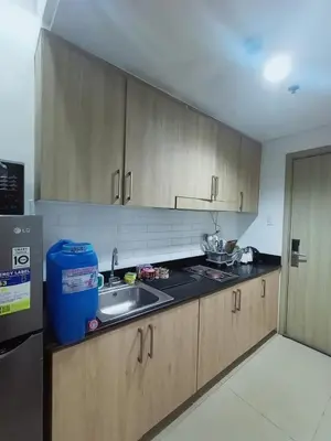 a kitchen with wooden cabinets and a sink at Cozy Couple Room in Manila