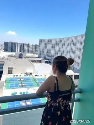 a woman standing on a balcony looking out at a stadium at Condo Azure Urban Resort Paranaque in Manila