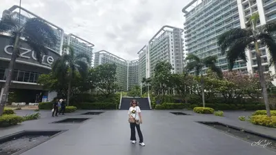 a woman is standing in front of a building at Condo Azure Urban Resort Paranaque in Manila